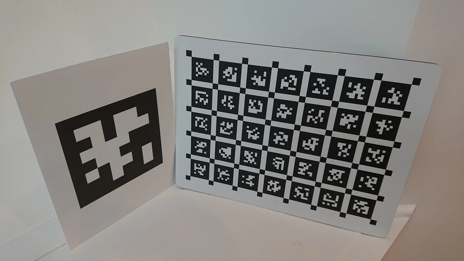 Un AprilTag grande y un tablero con decenas de AprilTags pequeños apoyados contra una pared