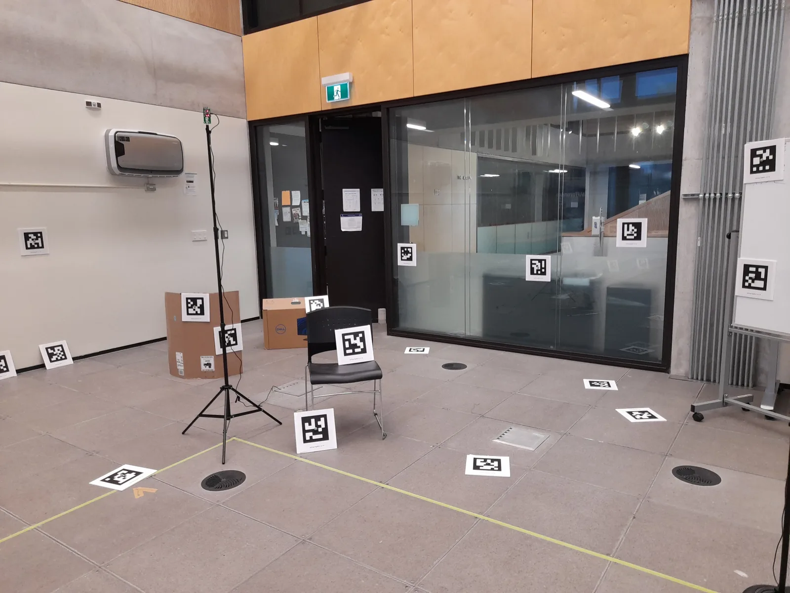 Una sala con AprilTags en el piso, las paredes y las cajas